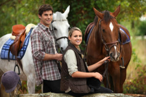 Smiling young couple holding the reins of beautiful horses in Helen GA